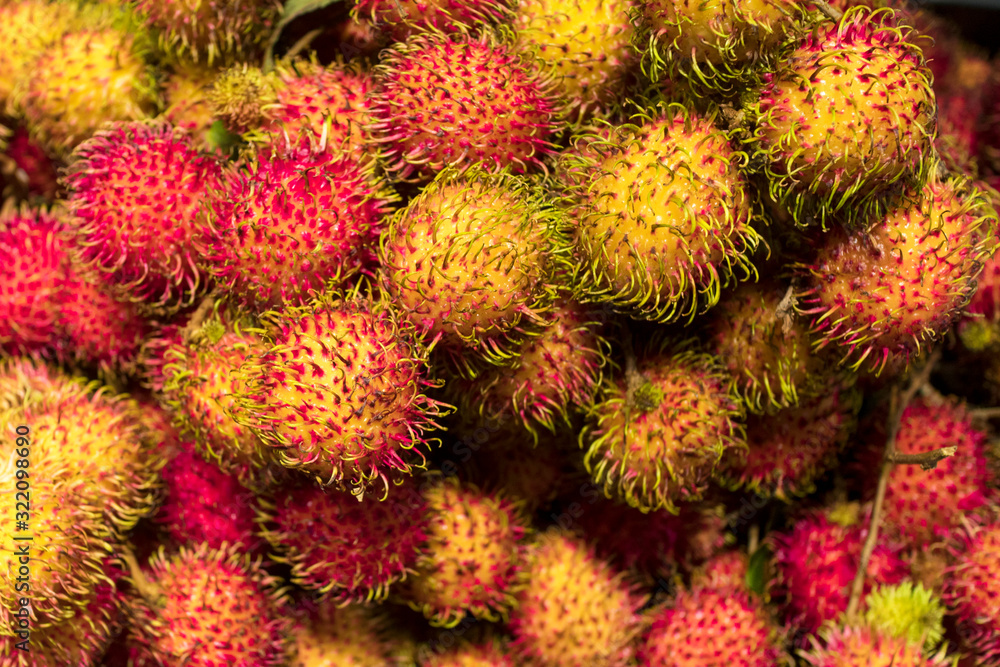 Close up, background of red and yellow rambutans, hairy round exotic tropical fruits. Close up, background of red and yellow rambutans, hairy round exotic tropical fruits.