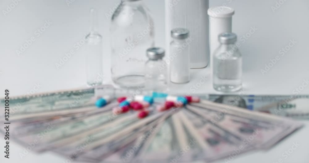 Bottles with liquid medication, tablets and dollar banknotes lying on table, pharmaceutical business, industry Bottles with liquid medication, tablets and dollar banknotes lying on table, pharmaceutical business, industry