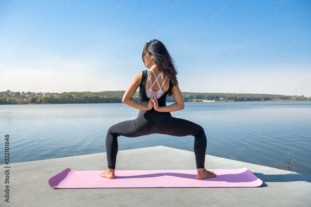 Young brunette woman  practicing yoga early morning before working time.  Concept of wellness and healthy lifestyle.
