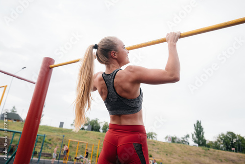 Sexy girl is pulled up on a horizontal bar in the open air. Fitness. Healthy lifestyle