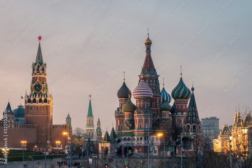 Spasskaya tower with watch of Moscow Kremlin architectural ensemble and Saint Basil's Cathedral at night.