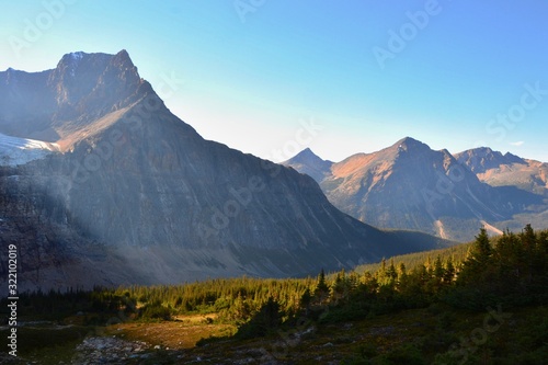 Fototapeta Naklejka Na Ścianę i Meble -  Panorama of Mount Edith Cavell. High mountains with glacier, sun rays illuminate the forest. Sunny day, blue sky, Canadian Rockies. 