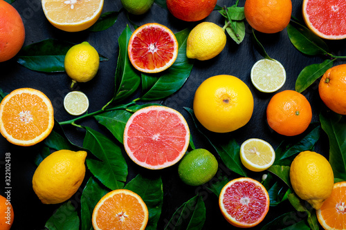 Frische Zitrusfrüchte mit Orangen, Zitronen, Pink Grapefruit und Limetten auf schwarzem Schiefer Hintergrund