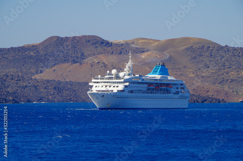 White classic Celestyal Cruises cruiseship or cruise ship liner anchored in bay of volcanic Greek Island of Santorini with cliffs and city of Oia in background in summer on blue sea and sky photo