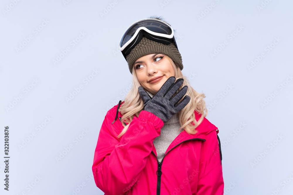 Skier teenager girl with snowboarding glasses over isolated blue background thinking an idea Skier teenager girl with snowboarding glasses over isolated blue background thinking an idea