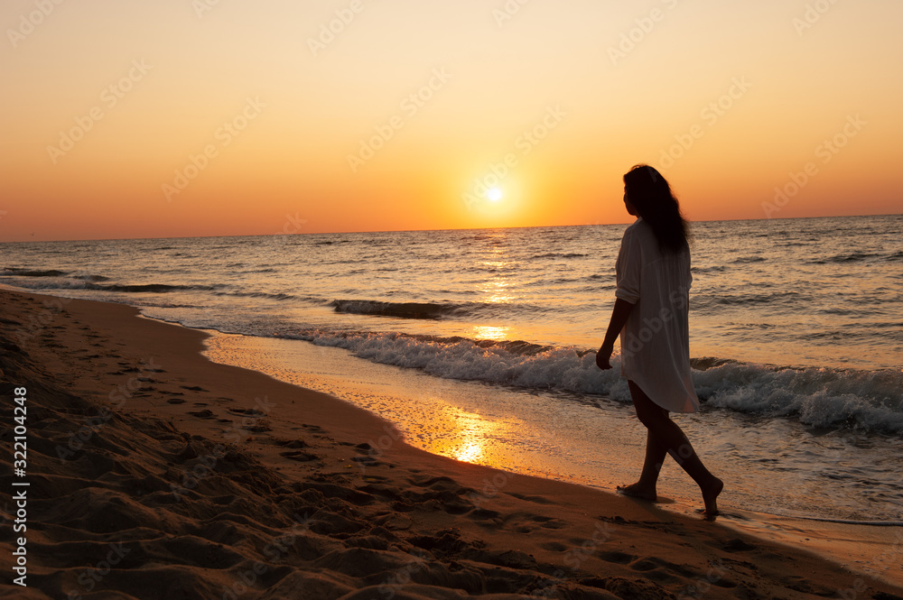 Girl walks along the coast at sunset, sunrise