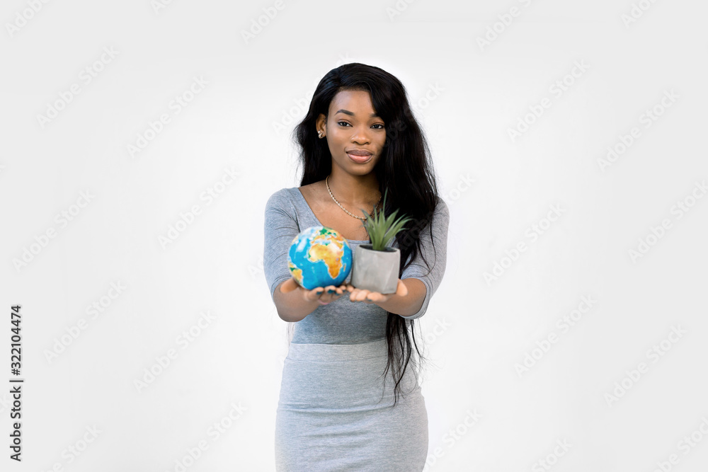 Beautiful smiling African woman showing planet earth globe and succulent in a pot in hands, focus on woman face. Earth day, international, nature and environment protection concept Beautiful smiling African woman showing planet earth globe and succulent in a pot in hands, focus on woman face. Earth day, international, nature and environment protection concept