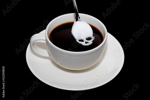 Unhealthy white sugar concept. Scull spoon with sugar and cup of black coffee