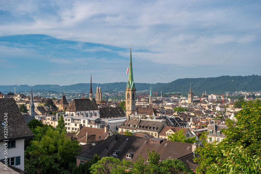 Panoramic view of the roofs of Zurich city with towers and steeples, Switzerland. In the distance, the Swiss Alps are visible.
