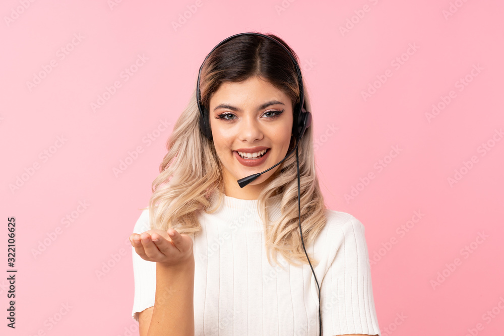 Teenager girl over isolated pink background working with headset Teenager girl over isolated pink background working with headset