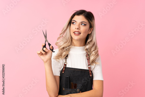 Foto Teenager girl over isolated pink background with hairdresser or barber dress loo