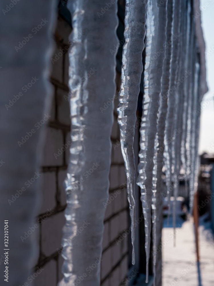 Icicles hang under toof of country house. Cold winter february Icicles hang under toof of country house. Cold winter february