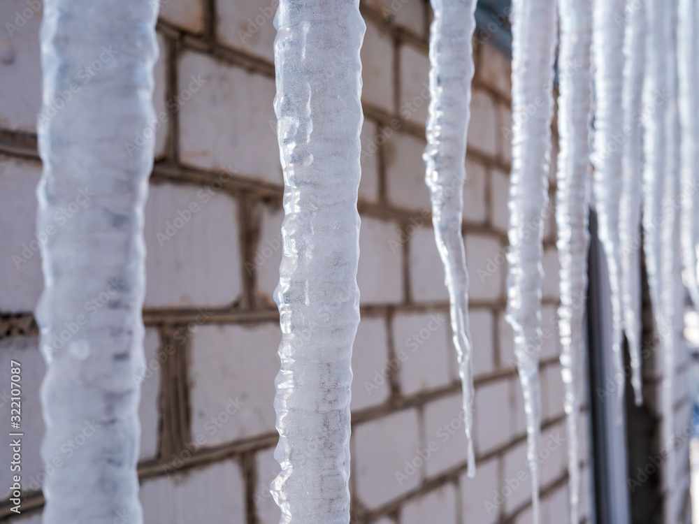 Icicles hang under toof of country house. Cold winter february Icicles hang under toof of country house. Cold winter february