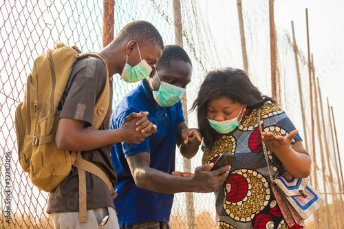 young black people wearing face masks having a conversation, checking something on a smartphone