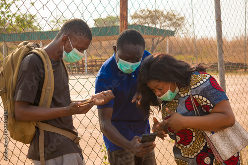 young black people wearing face masks having a conversation  checking something on a smartphone