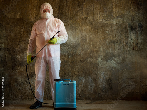 elderly man in protective overalls, special glasses and bactericidal mask with blue electric spray. military pensioner is ready to fight coronovirus and treat room with special solution