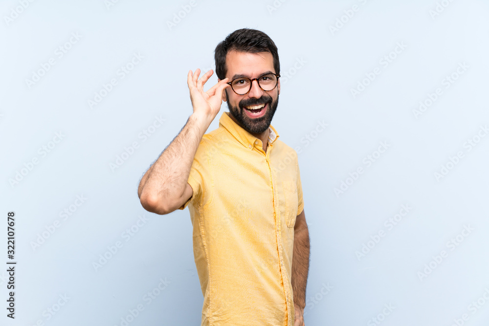 Young man with beard over isolated blue background with glasses and smiling Young man with beard over isolated blue background with glasses and smiling