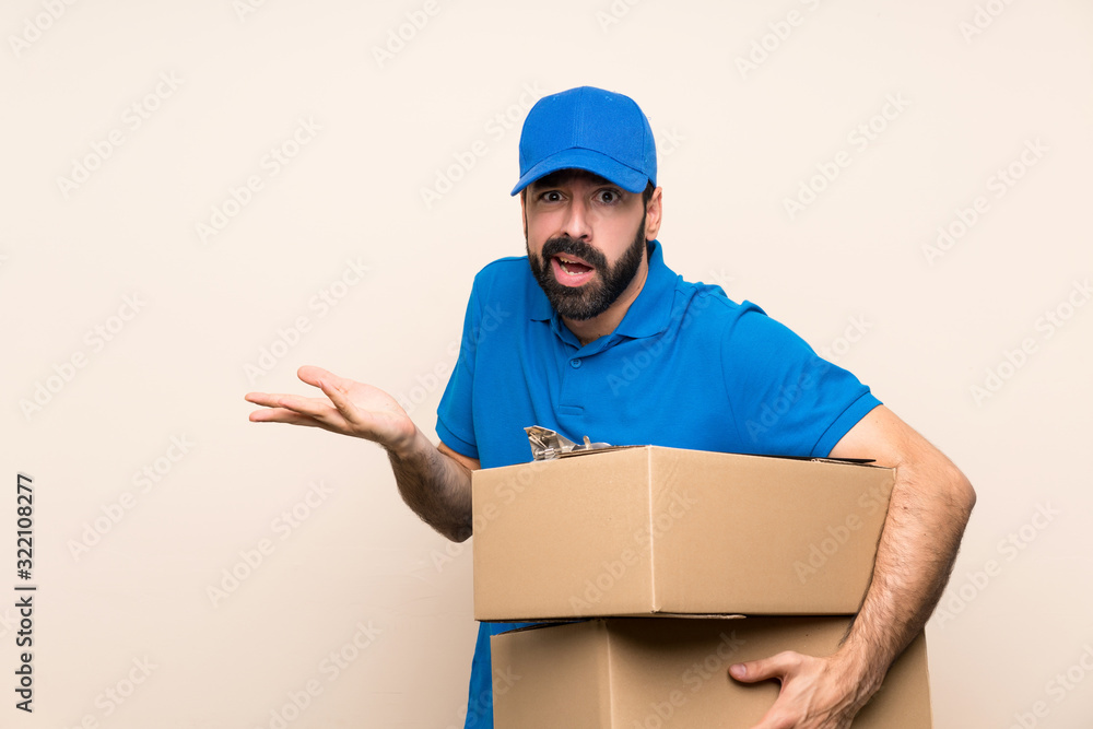 Delivery man with beard over isolated background unhappy for not understand something Delivery man with beard over isolated background unhappy for not understand something
