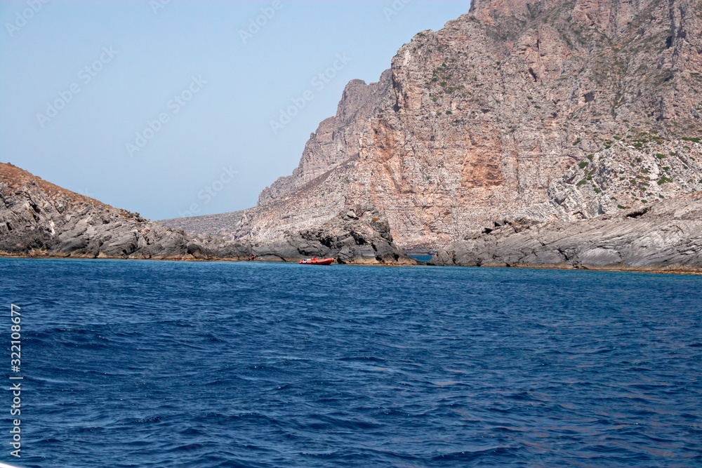 Some boats with tourists on board visit the rocky coast of the island of Marettimo, in the Egadi islands in Sicily, Italy.