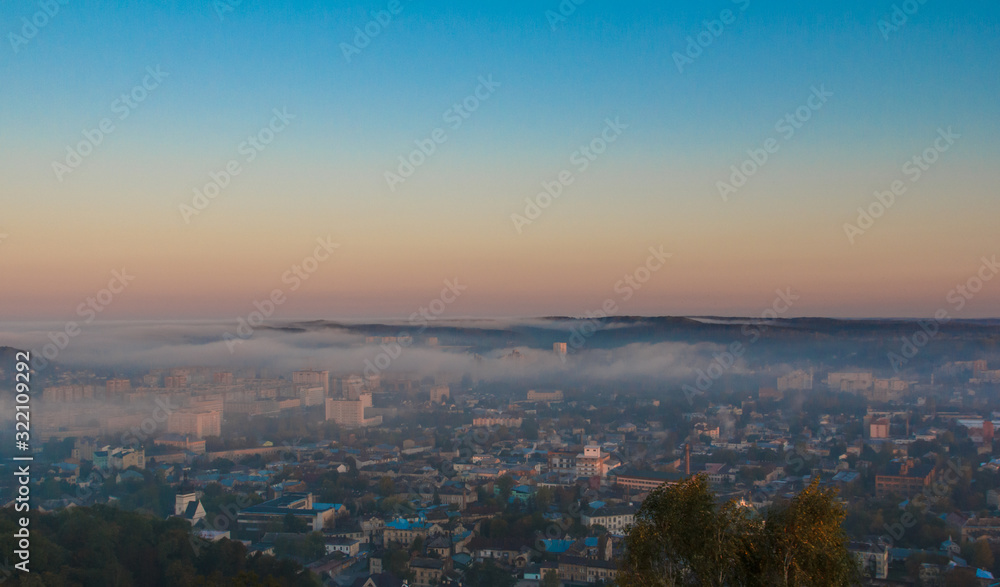 Dawn over the city in the fog