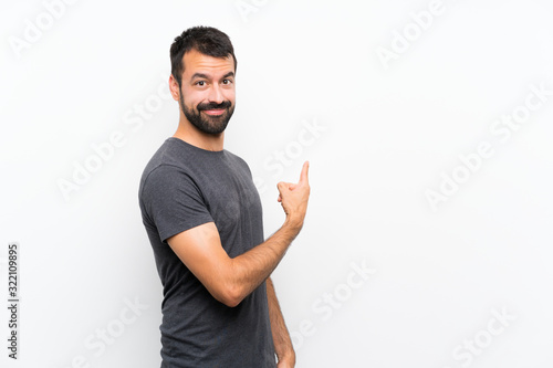 Tablou canvas Young handsome man over isolated white background pointing back