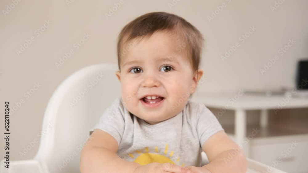 Adorable little happy laughing baby boy is looking to camera and smile. Baby looks around and smiles and laughs. 1 year old baby smiles and laughs at home Adorable little happy laughing baby boy is looking to camera and smile. Baby looks around and smiles and laughs. 1 year old baby smiles and laughs at home