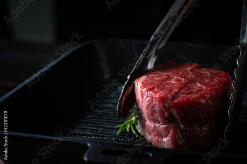 Schilderij op canvas Chef roasts filet Mignon beef steak in a pan with tongs