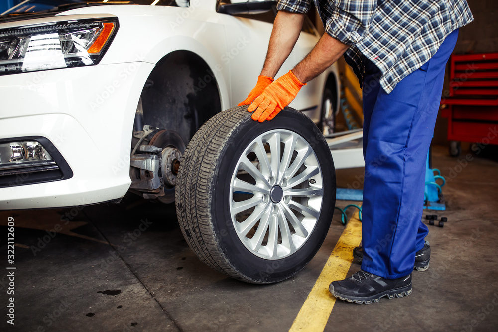close up of repairman in workshop changing tire on th car close up of repairman in workshop changing tire on th car