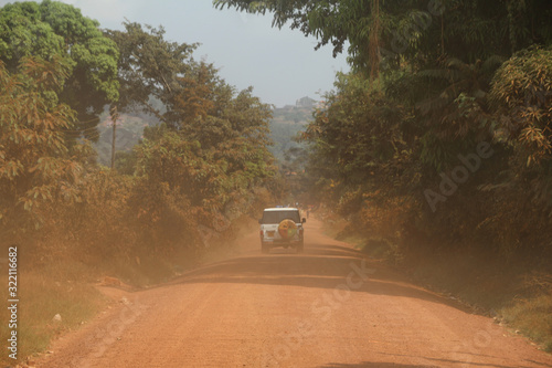 auto terenowe jadące po szutrwoej drodze wśród dziekij roślinności na afrykańskiej sawannie © KOLA  STUDIO