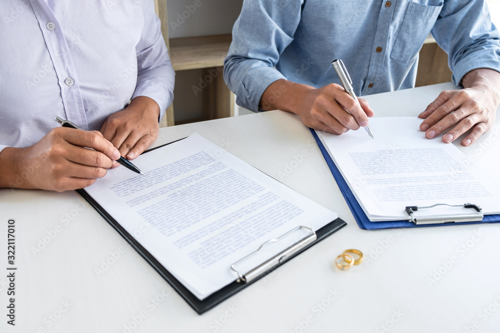 Young couple in the courthouse filing pen to signing divorce papers or premarital agreement, deciding on marriage divorce concept Young couple in the courthouse filing pen to signing divorce papers or premarital agreement, deciding on marriage divorce concept