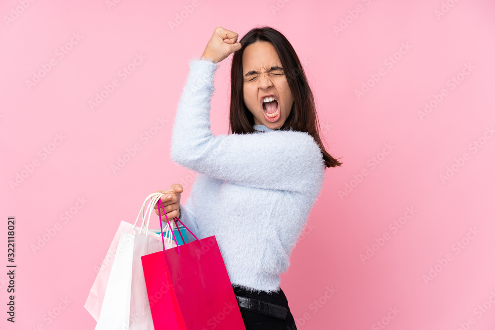 Young woman with shopping bag over isolated pink background doing strong gesture Young woman with shopping bag over isolated pink background doing strong gesture