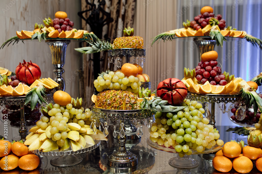 Fresh organic fruits background. Healthy eating concept. Fresh, exotic, organic fruits, light snacks in a plate on a buffet table. Luxury wedding catering. Delicious fruit at wedding reception.