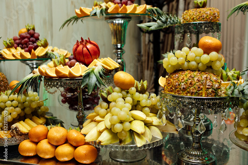 Fototapeta Naklejka Na Ścianę i Meble -  Fresh organic fruits background. Healthy eating concept. Fresh, exotic, organic fruits, light snacks in a plate on a buffet table. Luxury wedding catering. Delicious fruit at wedding reception.