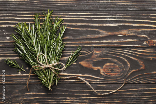 Flat lay composition with fresh rosemary on wooden background, space for text