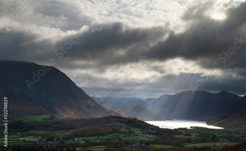 Majestic sun beams light up Crummock Water in epic Autumn Fall landscape image with Mellbreak and Grasmoor