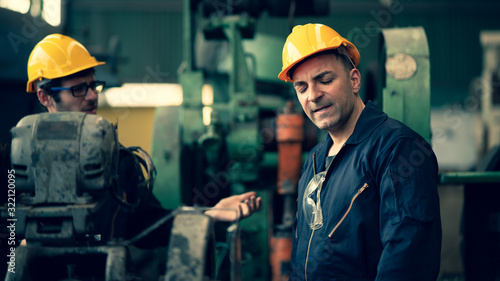 Scene shot of 2 industrial workers feeling upset with the engine machine of the factory, arguing planning, the procedure of work in the factory, concept industrial worker life, working confliction. photo