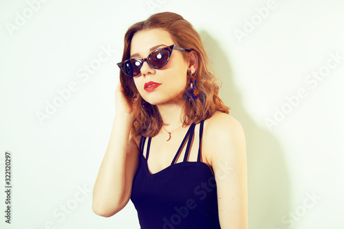 Hipster girl whole in a black dress, on a white background. Girl in unusual sunglasses and earrings. Fashion girl © MoreThanProd