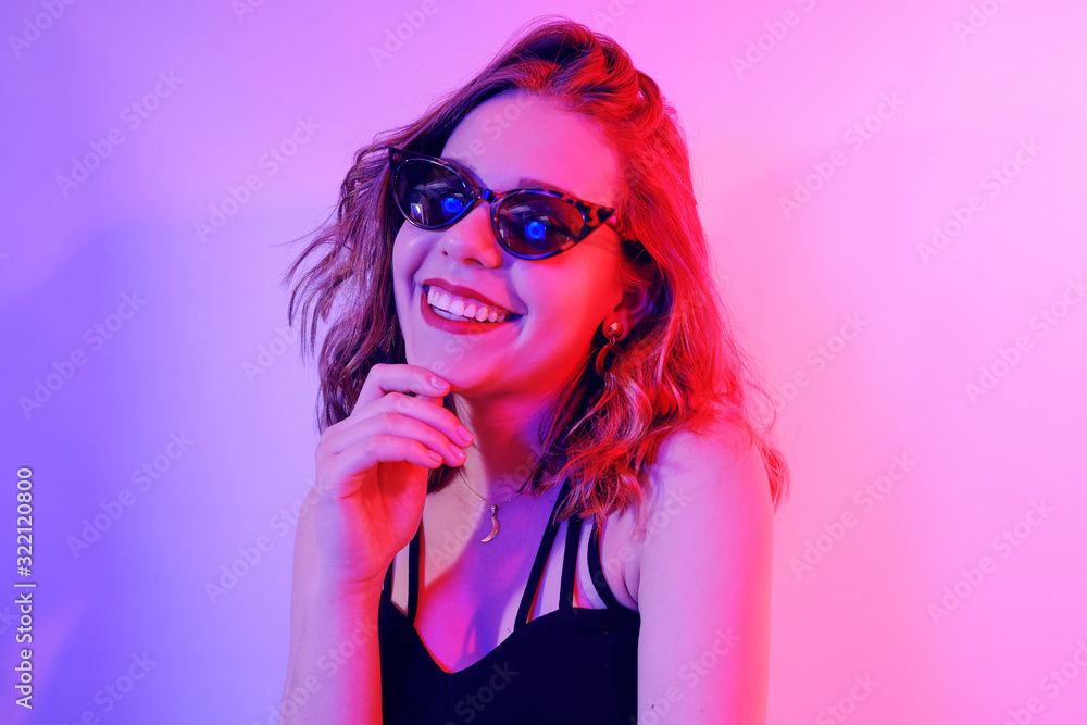 Beautiful girl in neon. Fashion photo of a short-haired girl, dancing, sun glasses. Girl in red and blue light posing. Happy girl smiles, laughs, good emotions. Beautiful girl in neon. Fashion photo of a short-haired girl, dancing, sun glasses. Girl in red and blue light posing. Happy girl smiles, laughs, good emotions.