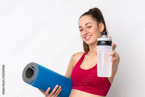 Young sport brunette woman over isolated white background with sports water bottle and with a mat