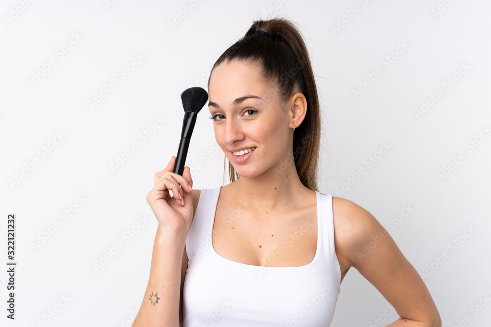 Young brunette woman over isolated white background holding makeup brush Young brunette woman over isolated white background holding makeup brush