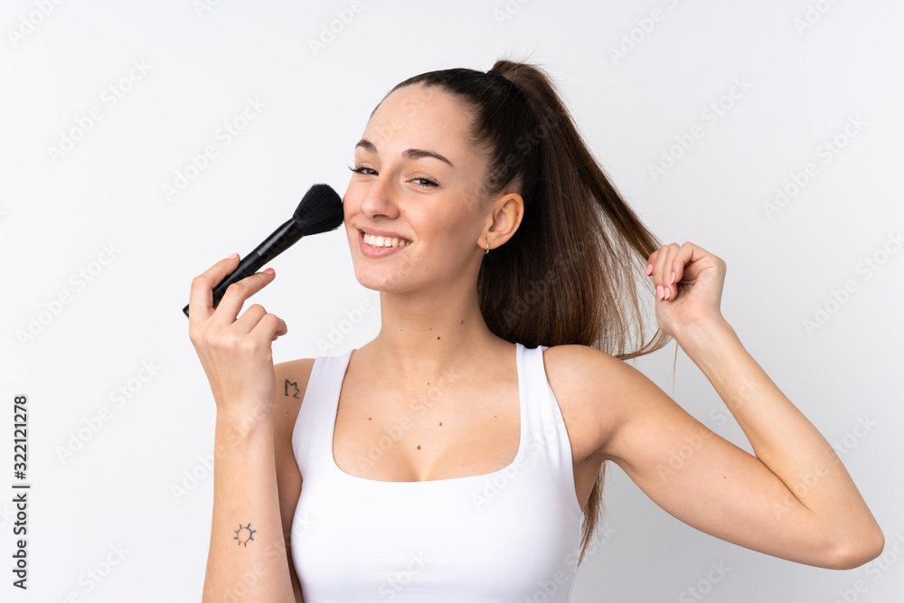Young brunette woman over isolated white background holding makeup brush Young brunette woman over isolated white background holding makeup brush