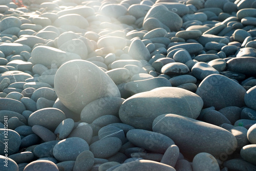 A beam of sunlight shines onto a rock in a collection of pebbles