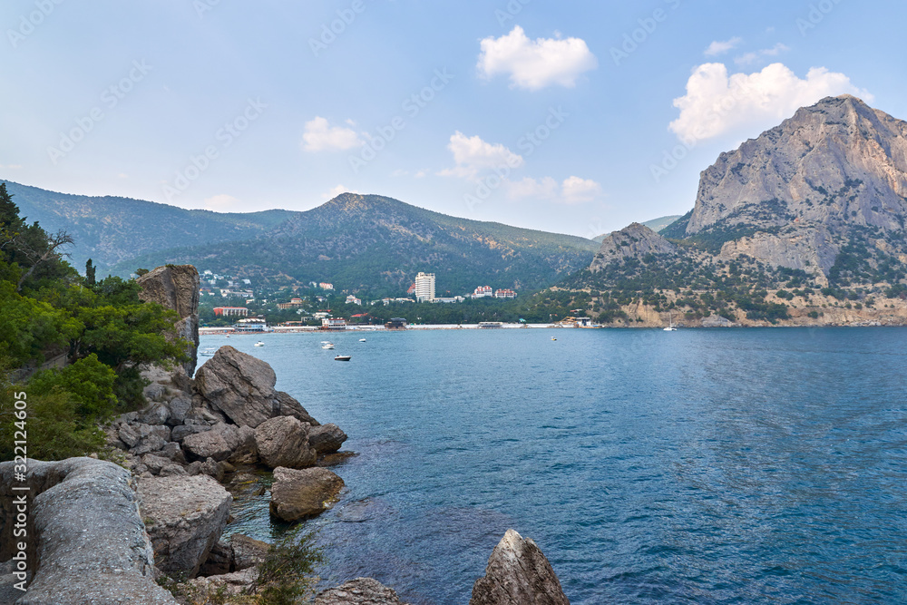 View of the Green Bay in the village of New World, coastal cliffs and a ridge of mountains on the horizon. View of Mount Falcon. Black Sea coast, Sudak region, Republic of Crimea