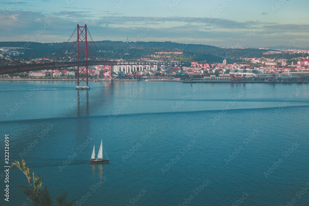 Puente rojo de Lisboa sobre el oceano azul y un velero