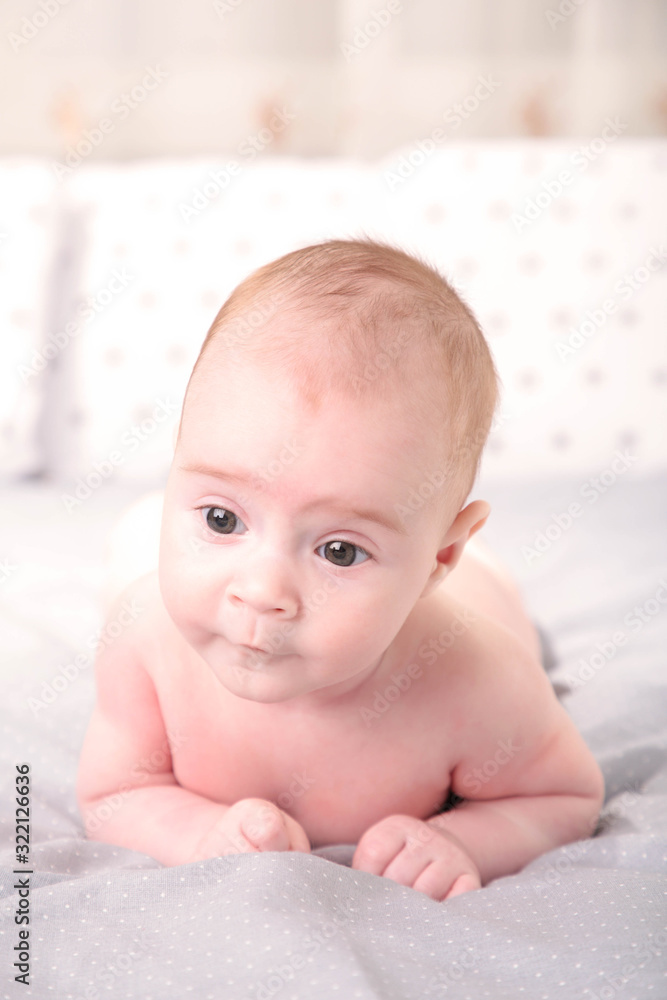 Happy young baby lying on tummy on a white background.