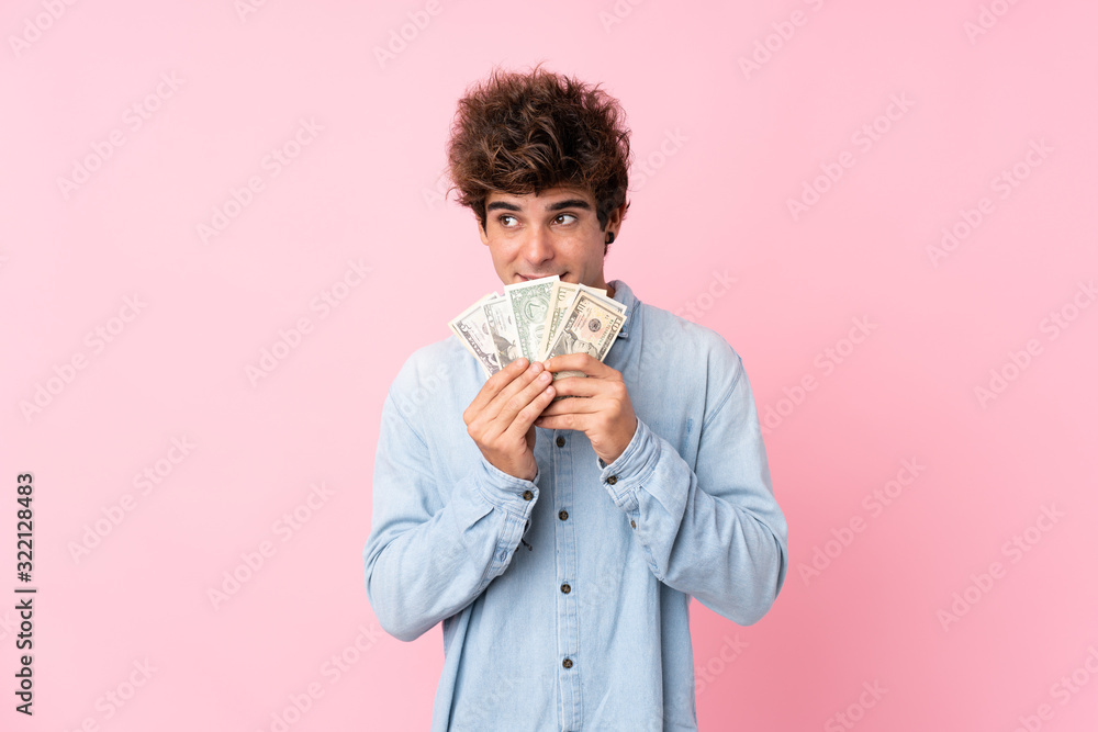 Young caucasian man over isolated pink background taking a lot of money Young caucasian man over isolated pink background taking a lot of money