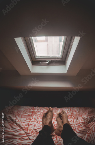 Pies de una pareja en la cama bajo ventana al amanecer.  photo