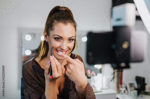 Quadro su tela Young beautiful woman and professional beauty make up artist vlogger or blogger recording makeup tutorial to share on website or social media