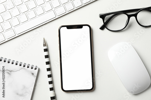 Workplace with phone with empty screen, top view