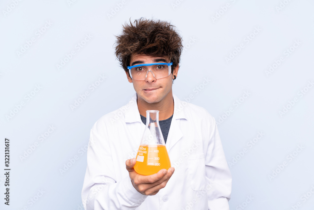 Young scientific man over isolated blue background having doubts and with confuse face expression Young scientific man over isolated blue background having doubts and with confuse face expression